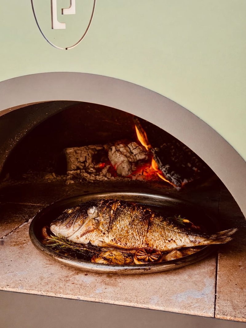 Whole fish cooking over the flame in Le Flambeur